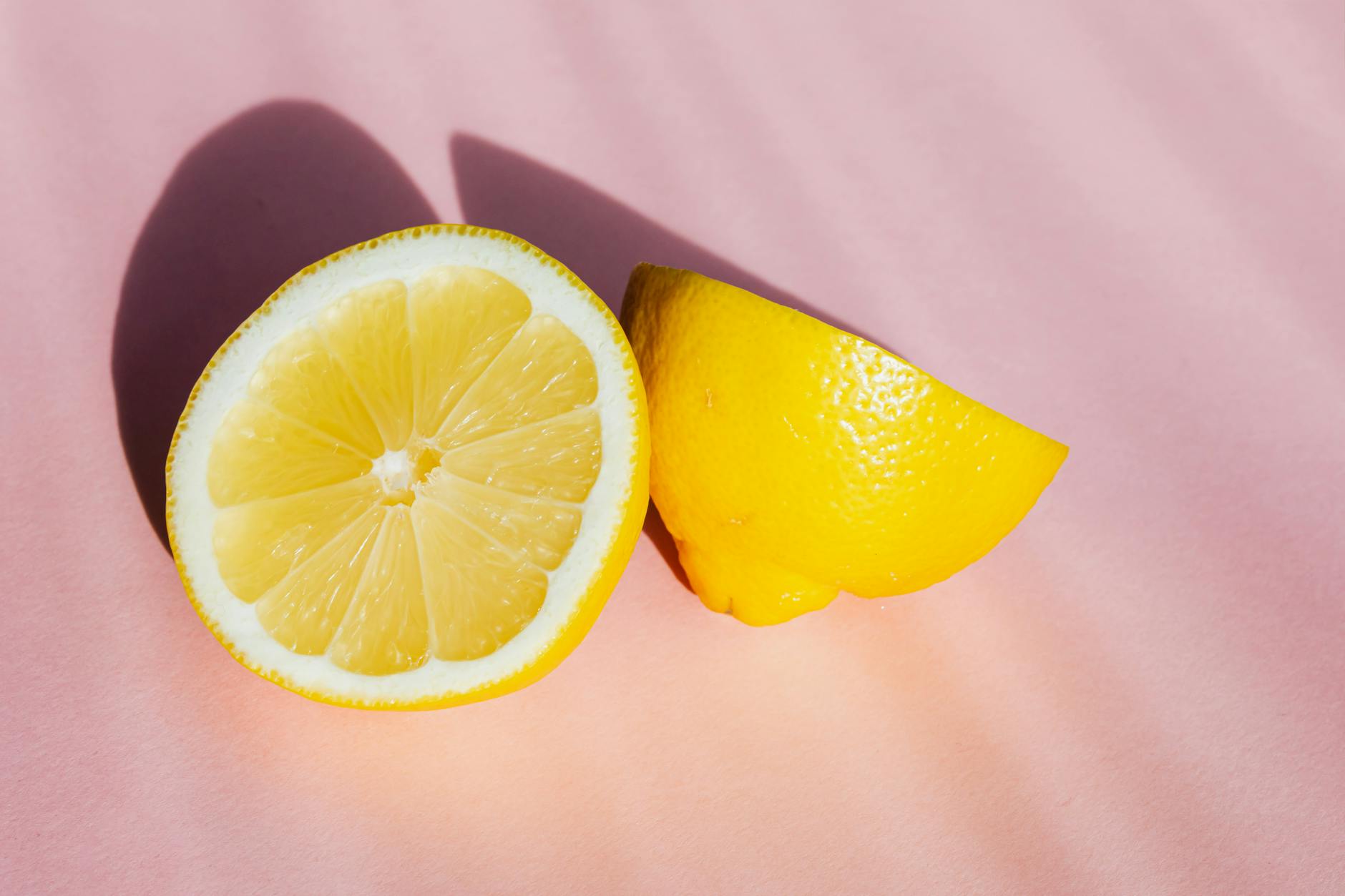 Fresh lemon halves on a pink background, symbolizing the citrus-inspired design of lemon vibrators and refreshed pleasure
