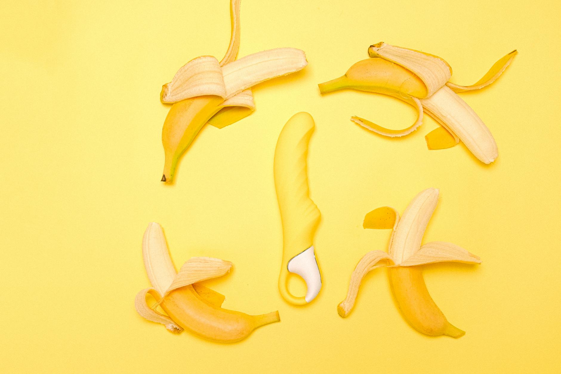 Yellow silicone vibrator surrounded by fresh lemons on a bright yellow background, representing renewal and recovery