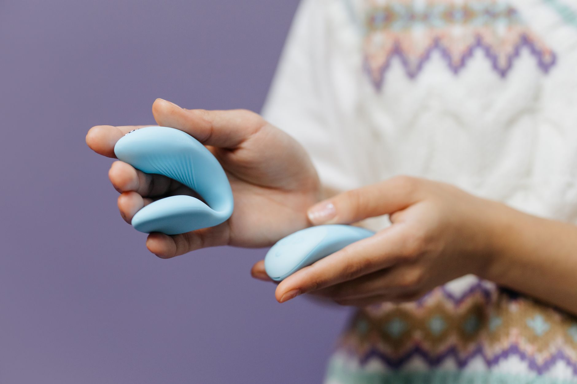Close-up of hands holding a sleek lemon vibrator against a purple background, symbolizing reconnection to pleasure