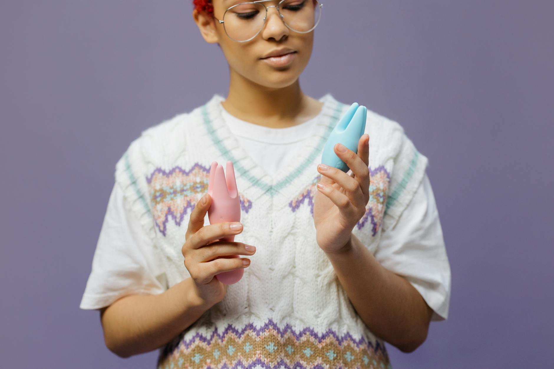 Woman holding colorful silicone vibrators thoughtfully, representing self-exploration with comfort and confidence