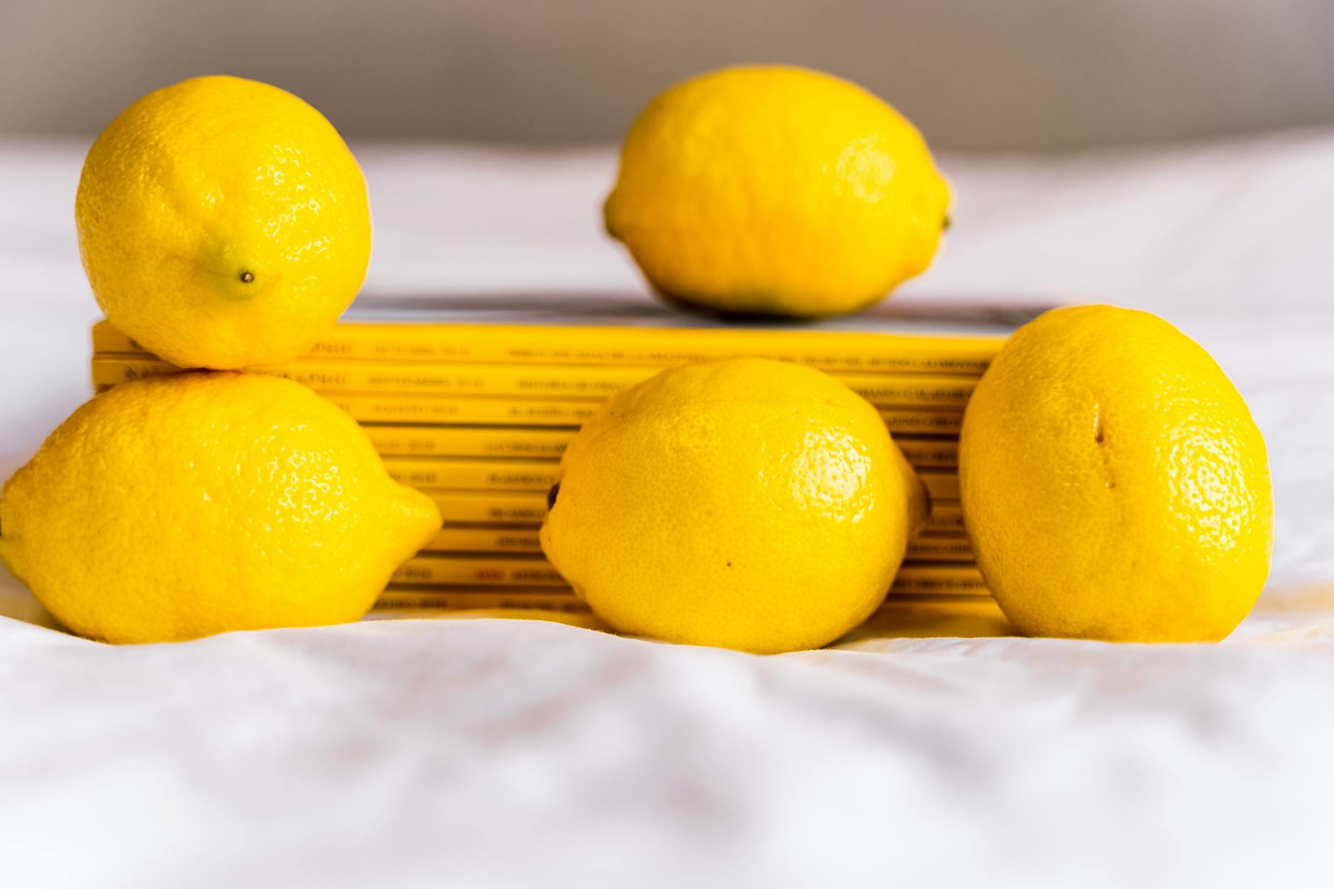 Fresh yellow lemons arranged on white tablecloth with stacked books, representing clarity and simplicity for beginners